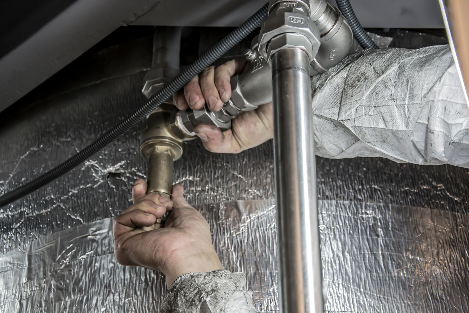 Hands fitting a brass valve onto a steel pipe